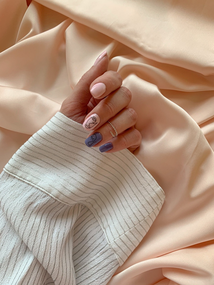 A single hand resting on cream silk fabric, fingers tipped with a soft mix of nude, lavender and minimal line-art designs on a builder gel base